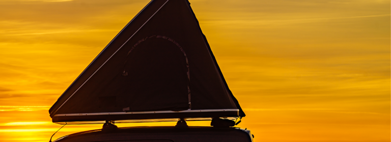 Die Silhouette eines Dachzelts vor einem Sonnenuntergang