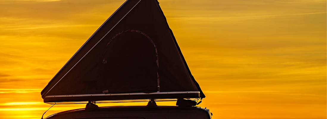 Die Silhouette eines Dachzelts vor einem Sonnenuntergang