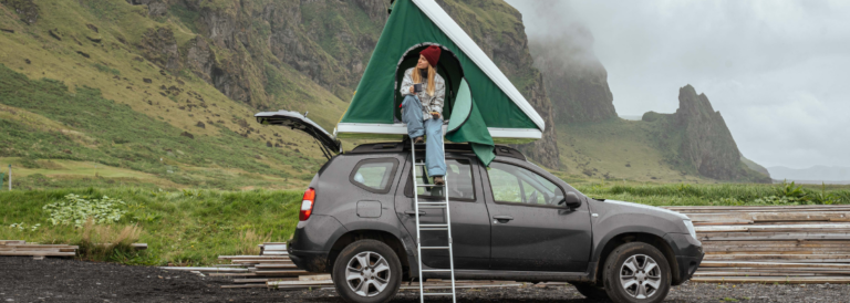 Frauen schauen sich etwas an, während sie im Zelt auf dem Dach ihres Autos sitzen