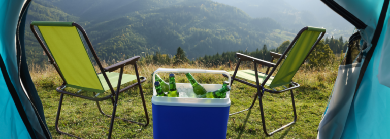 Stühle und Kühlbox mit Bierflaschen in Bergen, Aussicht vom Zelt.