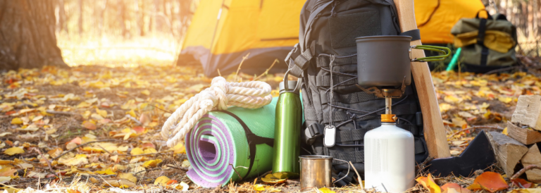 Touristische Überlebensausrüstung und Campingzelt im Herbstwald
